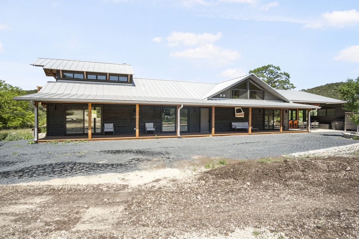High Places Ranch &mdash; modern dark-stained Hill Country home with metal roof and wraparound porch